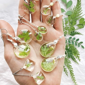 Detailweergave van hars hangers voor oorbellen met ingebedde echte groene varenbladen