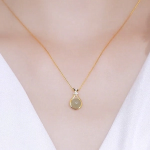 Gold necklace with Hetian jade fortune bag pendant on a model with white V-neck top
