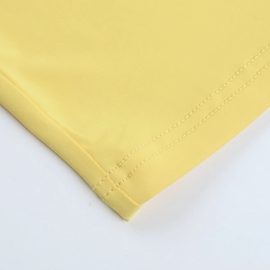Détail de la double couture de l'ourlet et texture du tissu sur une robe jaune