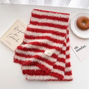 Detailed view of red and white striped wool scarf with ins tag on a cozy table