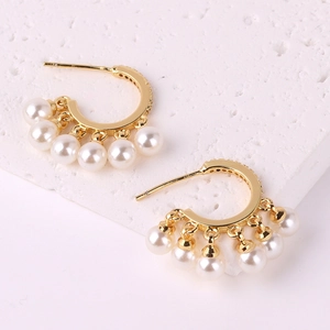 Elegant gold pearl tassel earrings with five white pearl pendants on textured marble
