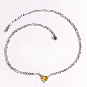 Macro detail of silver tennis necklace featuring a vibrant yellow heart-shaped zircon pendant