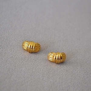 Macro shot of gold-plated striped stud earrings with vintage French textured design