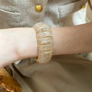 Detail of cream marbled resin elastic bracelet worn with elegant neutral fashion