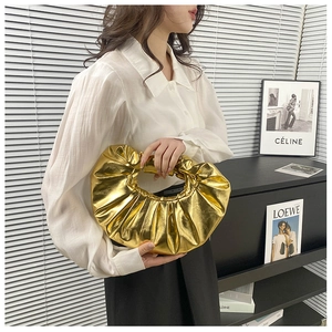 Detailaufnahme einer metallisch goldenen Handtasche mit Raffungen für einen schicken Look