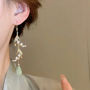 Elegant lily of the valley earrings with green water drop pendant on a female model