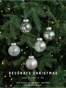 Close-up of five silver Christmas balls with glitter and beads hanging on a tree branch