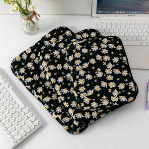 Three quilted daisy embroidery laptop sleeves in different sizes on a desk