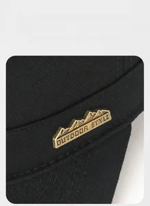 Detailed view of mountain metal logo and premium twill cotton fabric on black outdoor cap