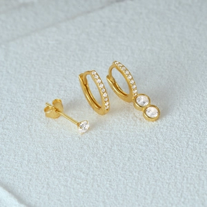 Detailed view of three-piece gold earring set with shimmering cubic zirconia stones