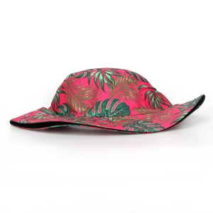 Detail of rose red sun hat featuring green tropical palm leaf and monstera prints