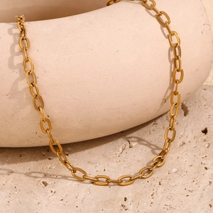 Detail of 18K gold plated stainless steel O-chain necklace links on textured stone