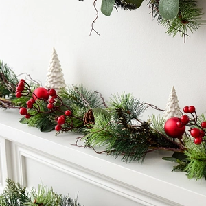 Christmas garland with pine needles and red berries on a white fireplace mantel decoration