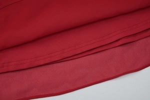 Détail de l'ourlet de la robe rouge montrant le tissu double couche et le tulle transparent