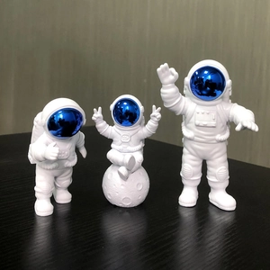 Three white astronaut figurines in different poses on a black surface with a moon model