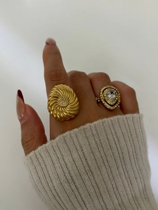 Close-up of golden double-layered rings with pavé diamonds and a teardrop crystal