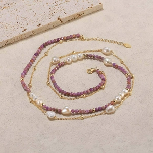 Detailed macro view of layered necklace featuring purple beads, pearls and gold chain
