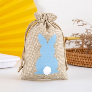 Detail of linen drawstring gift bag featuring a blue rabbit patch and white pom-pom tail