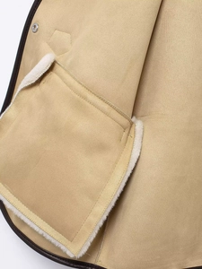Détail d'une veste en daim camel avec bordure en polaire et bouton-pression en métal