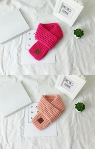 Detail of chunky knit winter scarves with leather EST LOVE label in pink and rose