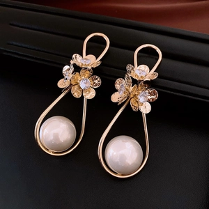 Macro shot of gold floral earrings with sparkling rhinestones and white pearls
