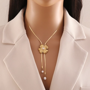 Golden flower Y-necklace with pearls and tassels shown on model with beige suit