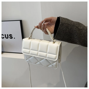 Detail of a beige quilted puff handbag with gold spherical hardware and top handle