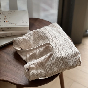 Detailed close-up of beige herringbone knit texture on a canvas shoulder bag
