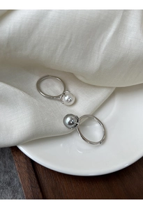 Dettaglio di anelli regolabili in argento con perle bianche e grigio-viola su tessuto