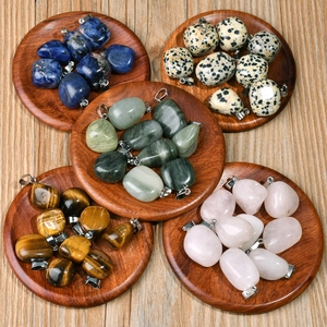 Close-up of assorted natural polished stones in a wooden tray with silver bails