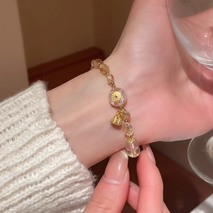 Detailed macro view of beaded crystal bracelet with golden lotus and bell charms on wrist