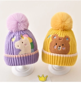 Close-up of knit dinosaur baby hats with fluffy pom-poms and cute animal embroidery
