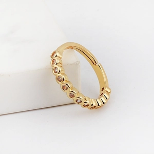 Gold-plated clicker ring with bezel-set clear zircons on a marble display stand