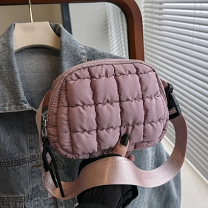 Close-up of pink quilted nylon crossbody bag with wide strap and zipper detail