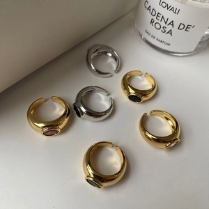 Dettaglio di anelli vintage in ottone con zirconi colorati su una superficie bianca