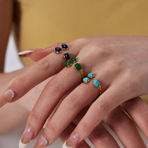 Detailed view of four adjustable gold-plated rings with colorful oval cabochon gemstones
