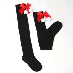 Detail of black over-the-knee socks with red satin bows and white fuzzy pom-poms