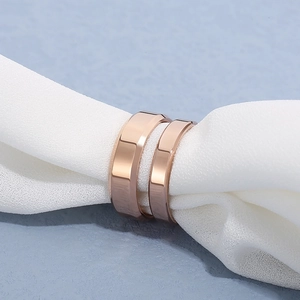 Close-up of two rose gold beveled edge rings resting on soft white fabric background