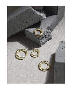 Set of four polished gold hoop earrings in varying sizes displayed on stone