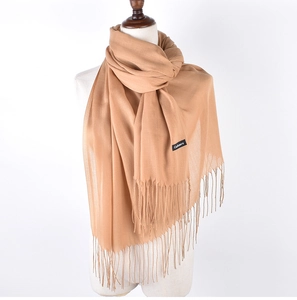 Detail showing high-quality camel cashmere texture and delicate fringe on the scarf