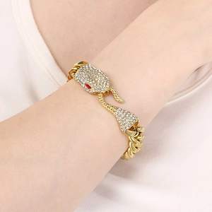 Gold-toned Cuban link bracelet featuring a crystal-encrusted snake head with red stone eyes