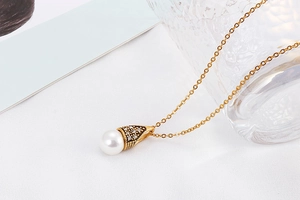 Detail view of a gold chain necklace featuring a white pearl pendant and crystal accents