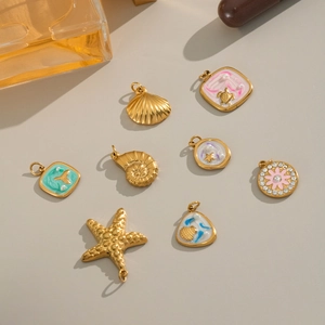 Flat lay of 8 gold ocean-themed pendants with enamel, pearls, and starfish details