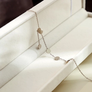 Close-up of minimalist silver bracelet with circular discs in a premium white jewelry box