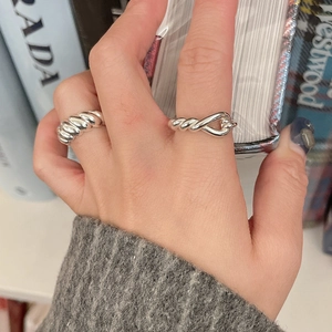 Macro view of sterling silver knot ring and textured croissant band set on finger