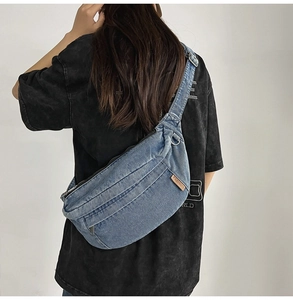 Close-up of denim cross-body bag featuring multiple zipper pockets and a fashion leather tag