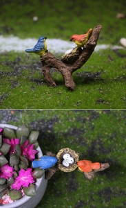 Detail view of miniature birds nest with colorful birds and eggs for garden landscaping
