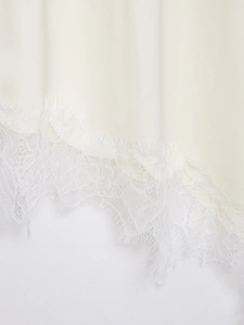 Detailed macro shot of premium lace trim and satin stitching on a cream women's top