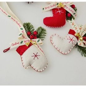 Dettaglio calza di Natale in feltro rosso e guanto bianco con pino e bacche rosse