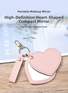 Close-up of pink heart-shaped leather makeup mirror with metal keychain hook and stitching